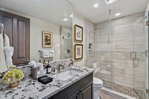A modern bathroom with a double sink vanity, a large mirror, framed artwork, and a walk-in shower. - Ski-In/Ski-Out Beaver Creek | Walk to Village (Beaver Creek)