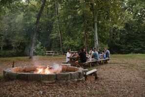 An outdoor gathering around a campfire with picnic tables, surrounded by trees. - Riverside house on a Duck River ranch: fishing lake, horses, covered deck (Normandy)
