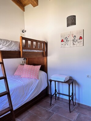 A bedroom with a wooden bunk bed, a small bedside table with a towel, and a wall-mounted light fixture. - Breathtaking Reservoir Views & Private Cave | 6-Bedroom Retreat Near Madrid (Alocén)