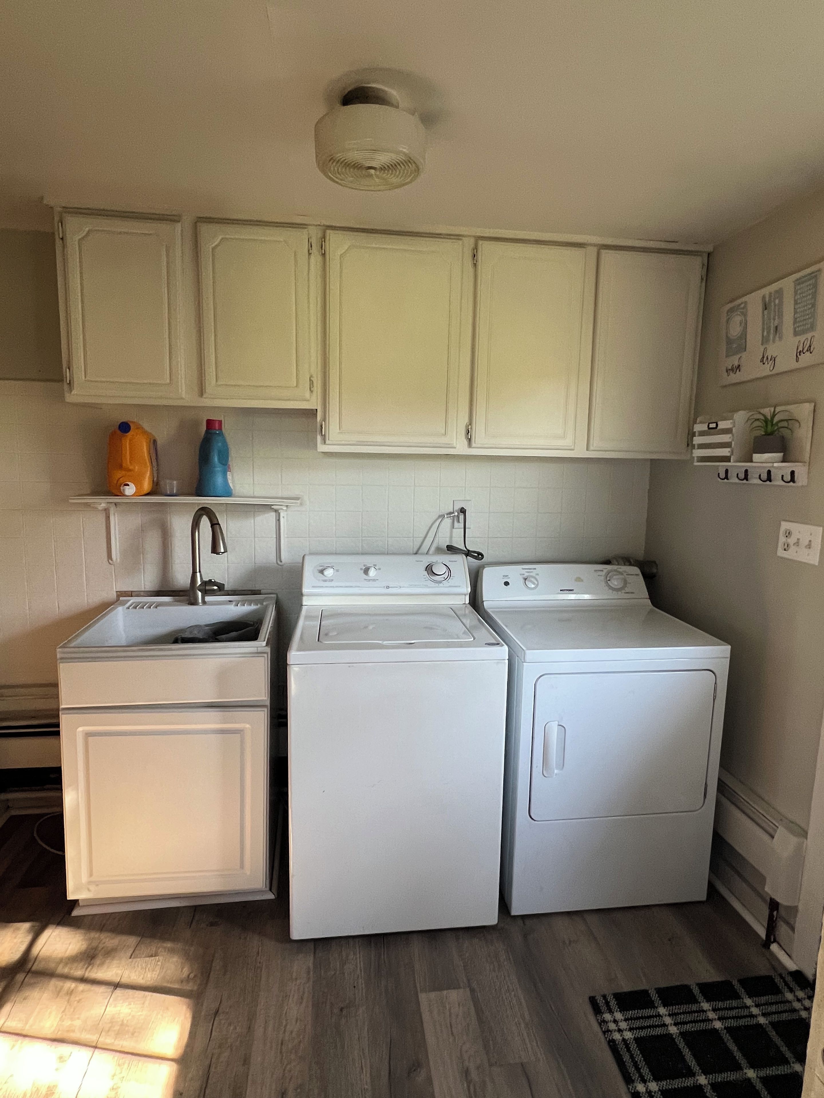 A compact kitchen with white cabinets, a sink, and two stacked washing machines.