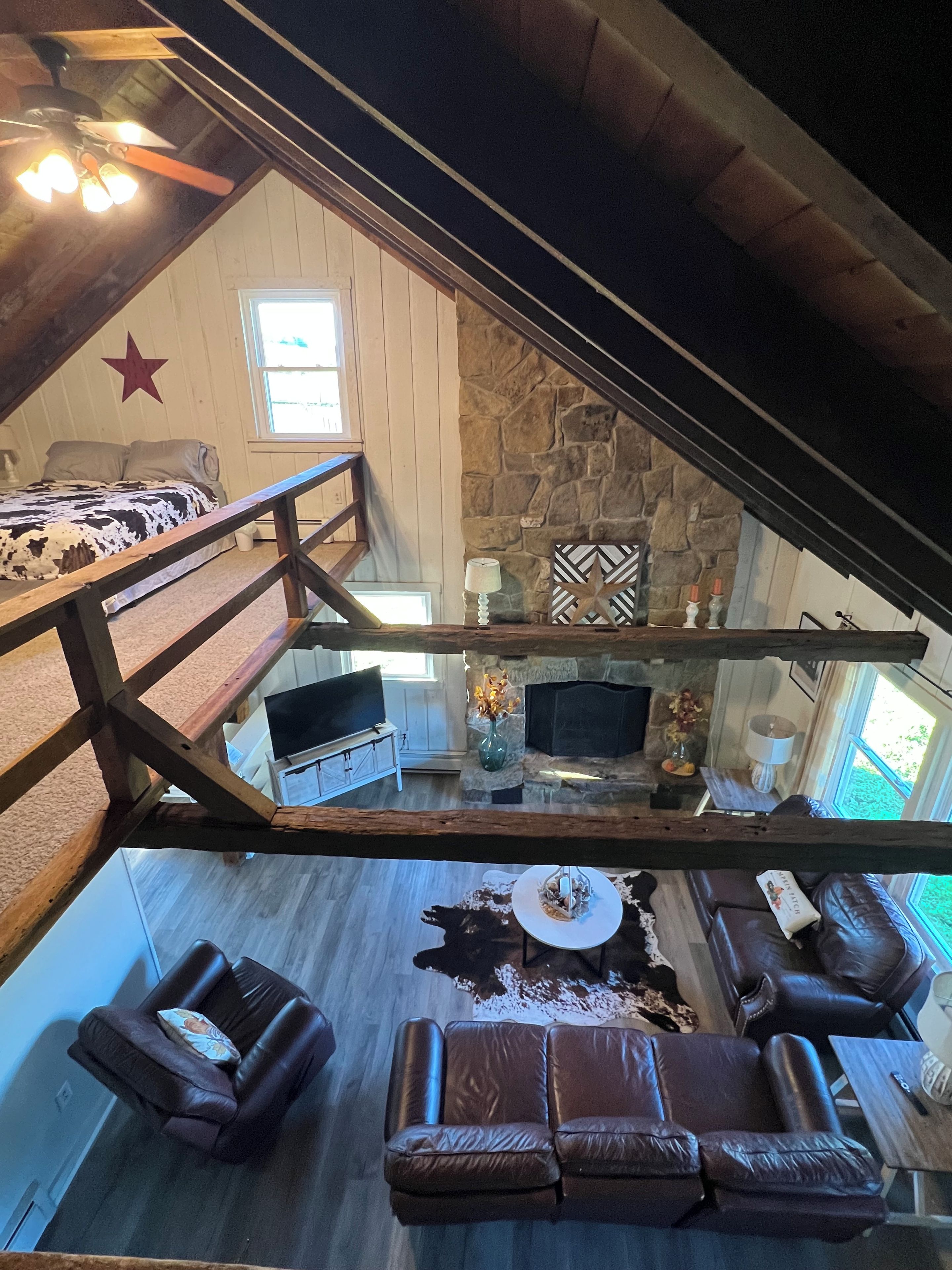 Un espacio habitable tipo loft con chimenea de piedra, muebles de cuero y vistas al exterior.