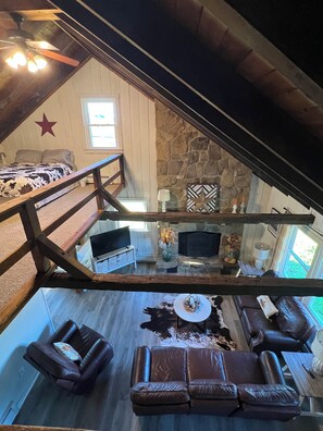 Un espace de vie de style loft avec une cheminée en pierre, des meubles en cuir et une vue sur l’extérieur.