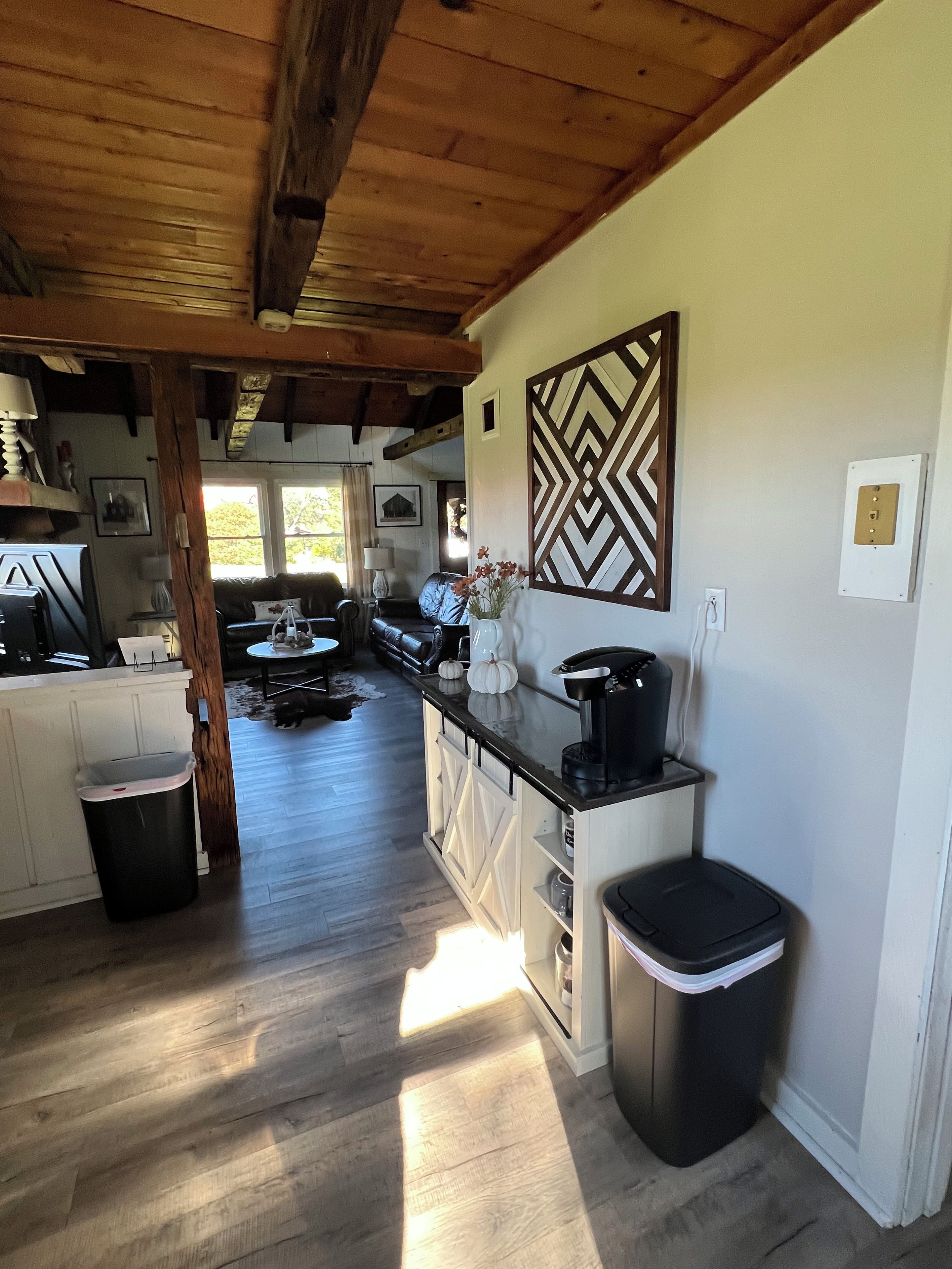 A kitchen with wooden beams, a white countertop, and a black trash bin.