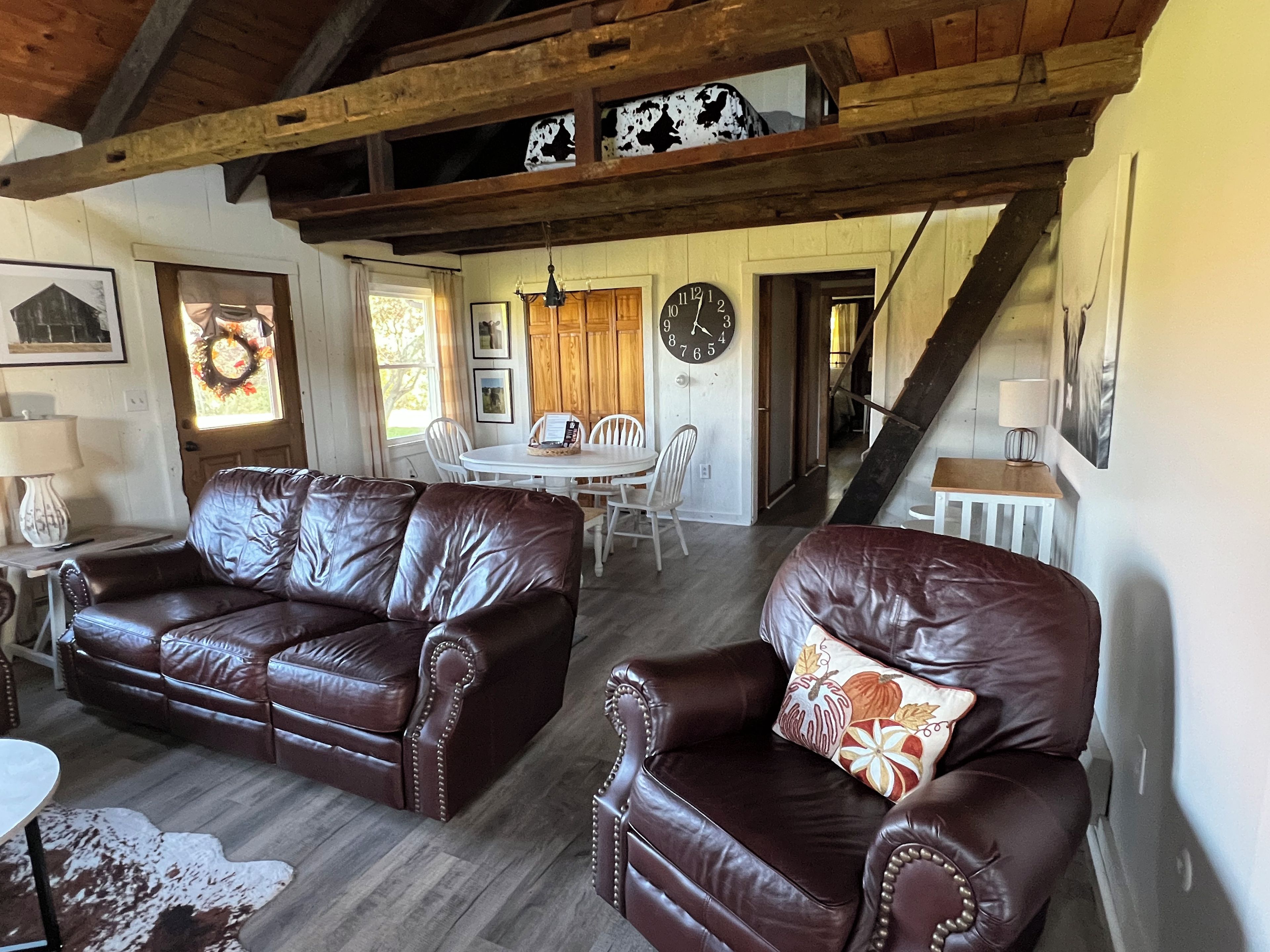 A living room with leather sofas, a dining table, and a staircase.