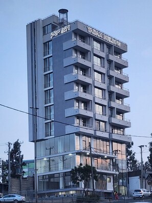 A multi-story building with balconies, a sign reading 'YADAM BUILDING,' and a visible entrance with glass doors. - Spacious 3BR Serviced Apartment Near Bole Airport (Addis Ababa)
