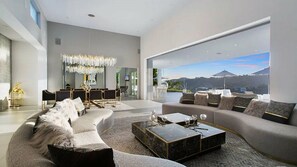 A modern living room with a curved sofa, a marble coffee table, and a chandelier. - Lemmer Grange (Los Angeles)
