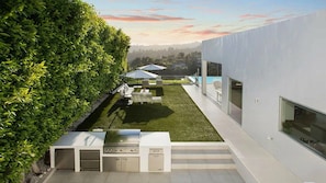 A modern outdoor kitchen area with a grill and seating, surrounded by a well-maintained lawn and a hedge. - Lemmer Grange (Los Angeles)