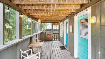 Une véranda couverte avec un plafond en bois, une table, des chaises et une vue sur l’extérieur.