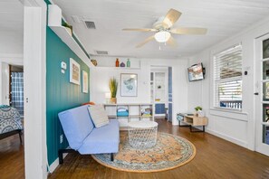Teal accent wall, plank floors and a cozy futon facing the smart TV upstairs, an easy place to put your feet up. - 2BR Duplex · Sleeps 6 · Private Hot Tub · Dogs OK (Saint Augustine)