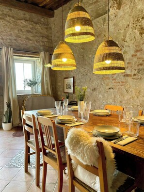 Ein Essbereich mit rustikaler Steinwand, Holztisch und Stühlen.