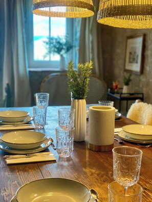A dining table set with plates, glasses, and a vase with greenery. - Medieval house with jacuzzi in Val di Cecina (Castelnuovo di Val di Cecina)