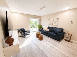 A modern living room with a sofa, two chairs, a coffee table, a TV, and a plant. - Walk to Shands Hospital & UF - Pool (Gainesville)