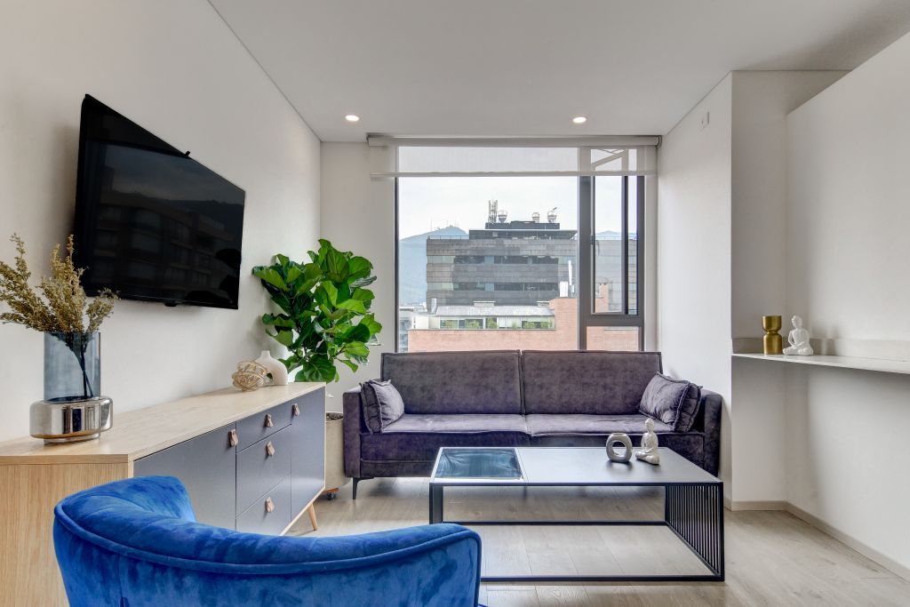 A modern living room with a sofa, a coffee table, and a television mounted on the wall.