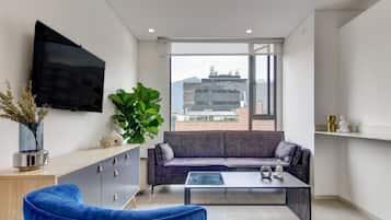 A modern living room with a sofa, a coffee table, and a television mounted on the wall.