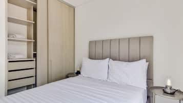 A bedroom with a bed, a nightstand, a bedside lamp, and a wardrobe.