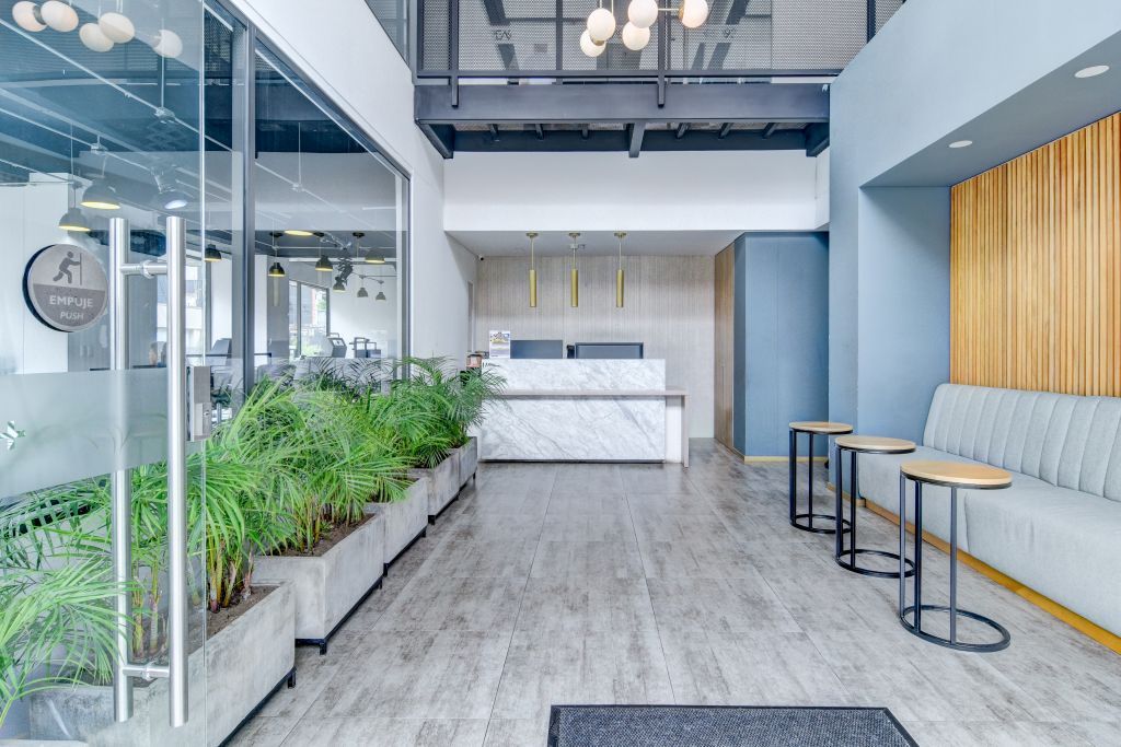 Una moderna zona de recepción con mostrador de mármol, asientos y plantas.