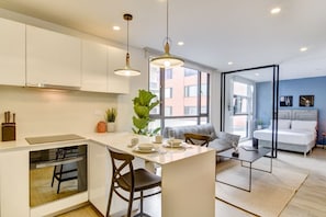 A modern kitchen with a dining area, a sofa, and a bed in the adjacent room. - Area 93 Plus (Bogotá)