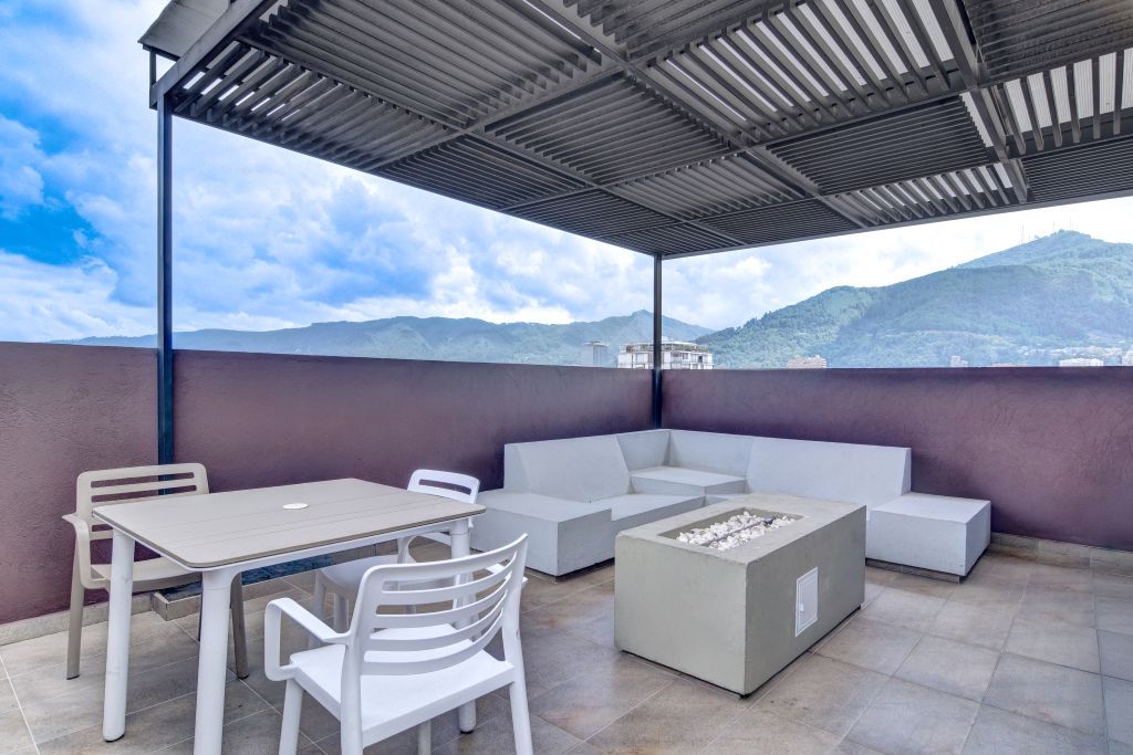 An outdoor patio with a table and chairs, a sofa, and a fire pit.
