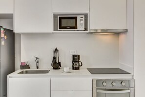 A kitchen with a microwave, coffee maker, and stove. - Area 93 Plus (Bogotá)
