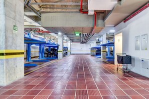 A spacious indoor area with a tiled floor, industrial-style blue machinery, and exposed ceiling pipes. - Area 93 Plus (Bogotá)