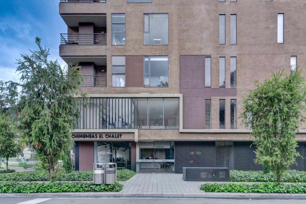 Un edificio de varios pisos con un espacio comercial en la planta baja, que incluye un restaurante visible llamado 'CHIMENEAS EL CHALET'.