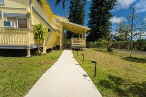 Ein gelbes Gebäude mit einer überdachten Veranda und einem Betonweg, der davor führt.