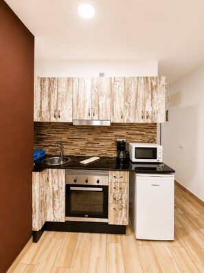 A compact kitchen with wooden cabinetry, a built-in oven, a microwave, and a coffee maker. - 404|Apartment with ocean views|Canteras Beach (Las Palmas de Gran Canaria)