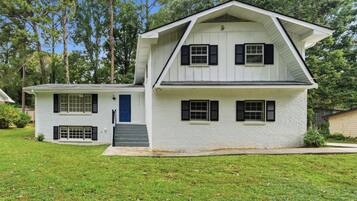 A two-story house with a front porch, a blue door, and a small front yard.