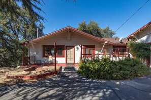A single-story house with a red roof, a front porch with a bench, and a small garden area. - Your Yosemite Basecamp with Amazing Deck Views just south of Yosemite Entrance (Oakhurst)