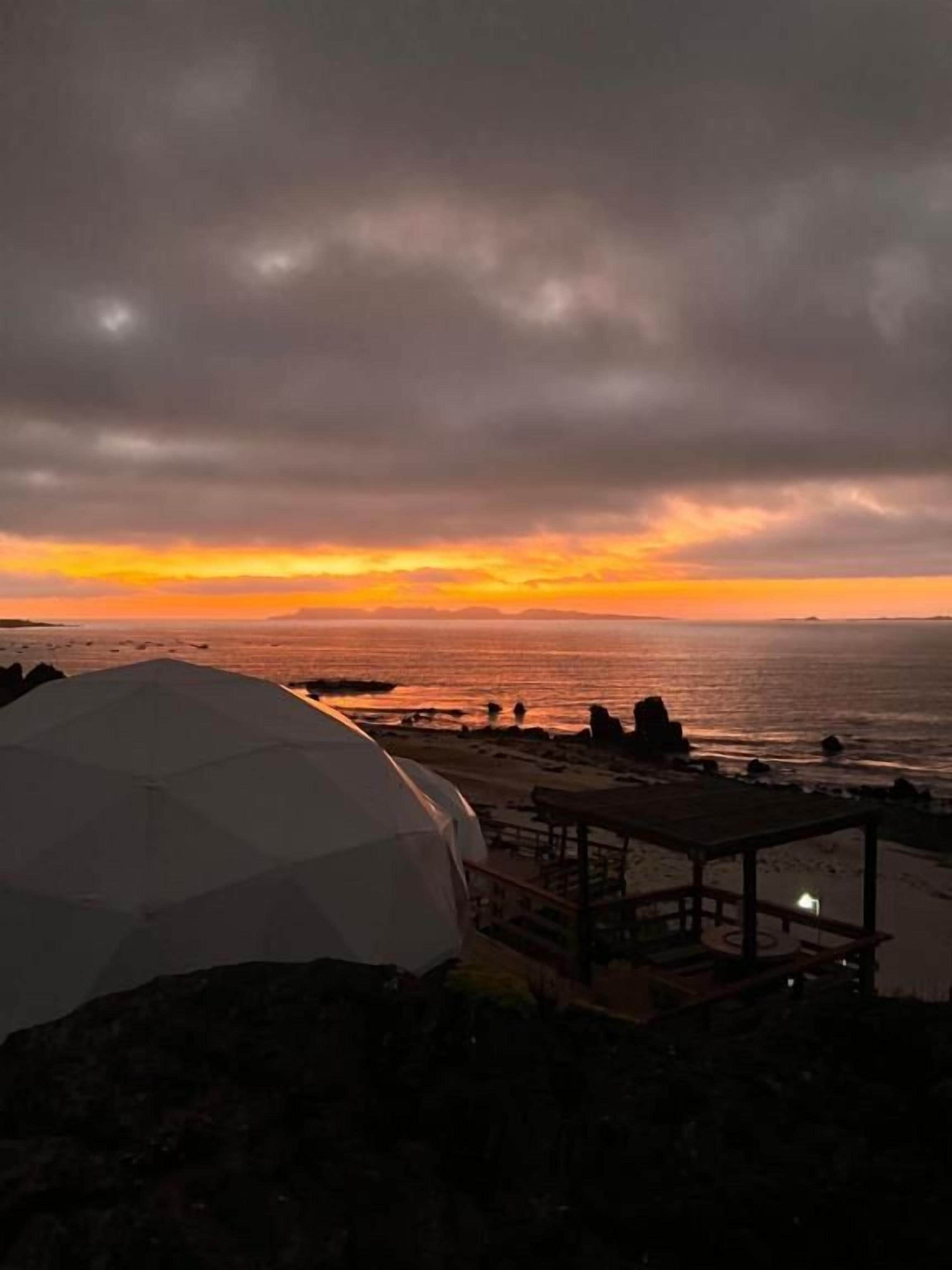 A beach scene with a dome-shaped structure and a wooden deck.