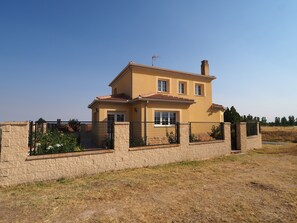 Une maison à deux étages avec un mur en pierre et une clôture en métal.