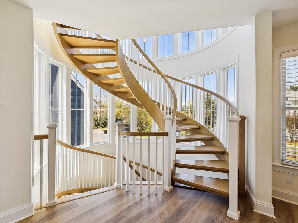 A spiral staircase with wooden steps and white balusters, leading to an upper floor.
