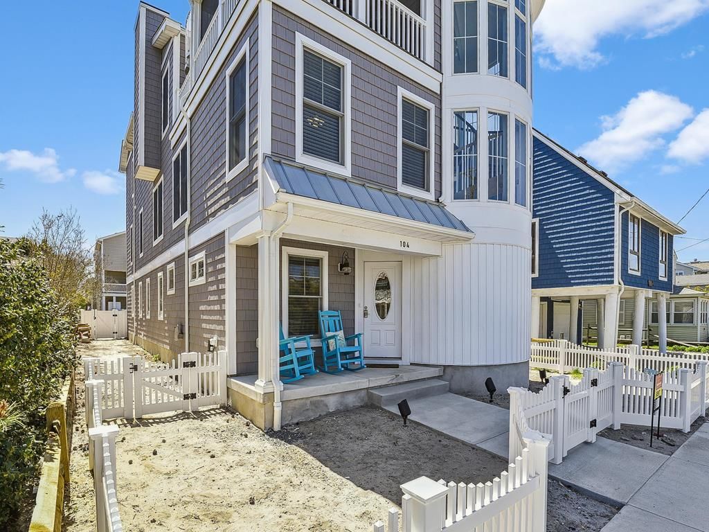 A two-story house with a front porch, a mailbox, and a small garden area.