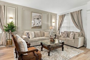 A living room with a sofa, armchair, coffee table, and decorative items. - 6BR Near Disney, Pool, Games and Themed Rooms (Kissimmee)