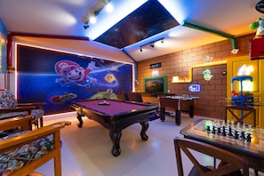 A room with a pool table, foosball table, and a gaming area with a neon sign. - 6BR Near Disney, Pool, Games and Themed Rooms (Kissimmee)