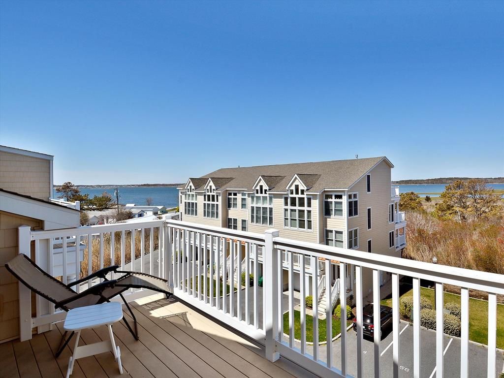 A balcony with a white railing overlooking a row of townhouses.
