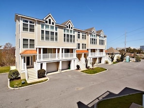 A multi-story hotel with a central courtyard, balconies, and a parking lot. - Beachside 4BR Condo w/ Ocean Views + Pool Access! (Fenwick Island)