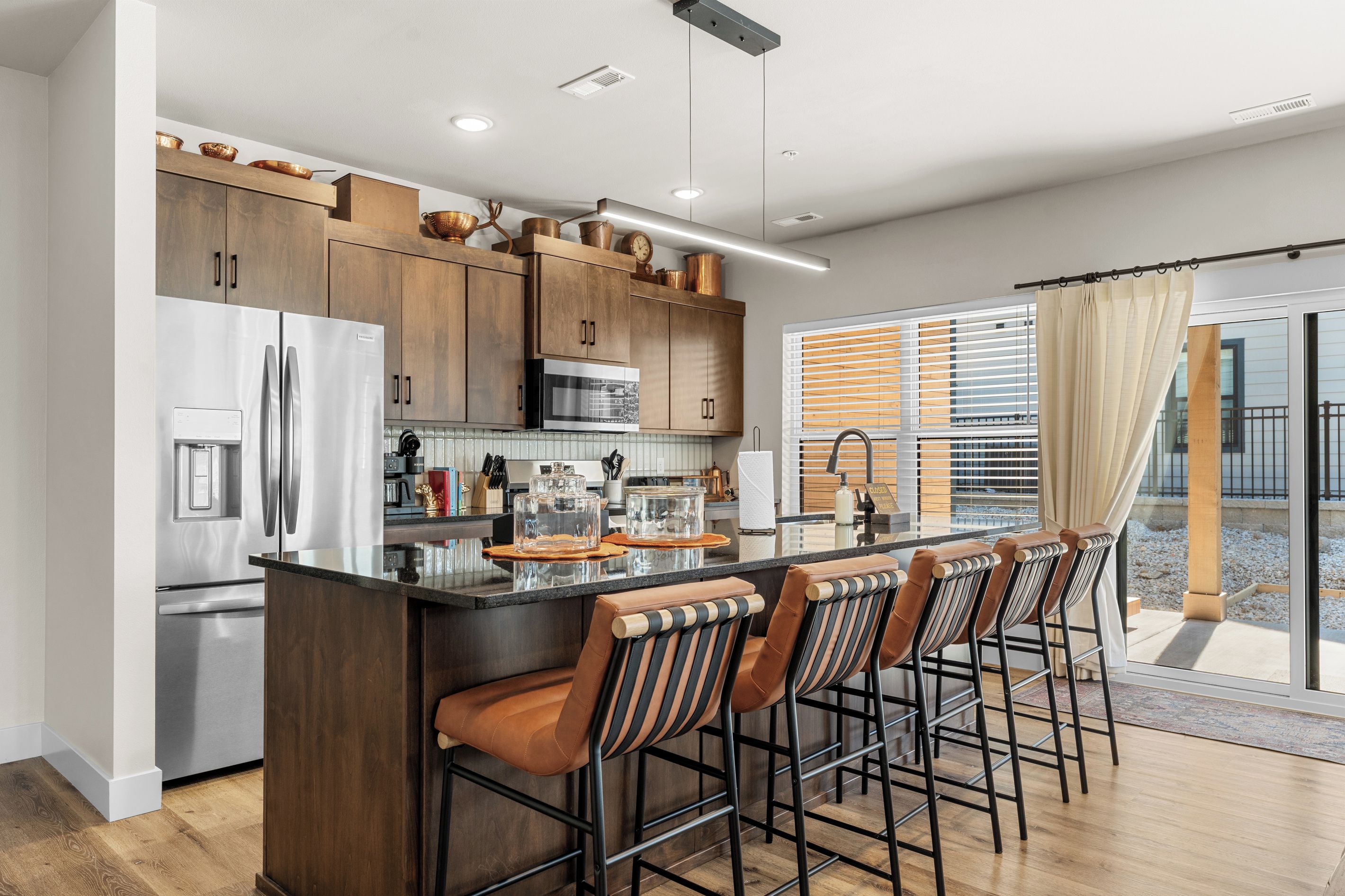 Una cocina moderna con una isla central, electrodomésticos de acero inoxidable y una zona de bar con taburetes.