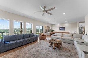 A spacious living room with a grey sectional sofa, a beige sofa, and a glass coffee table. - Taneycomo Wake & Lake | NEW • Private Pool (Branson)