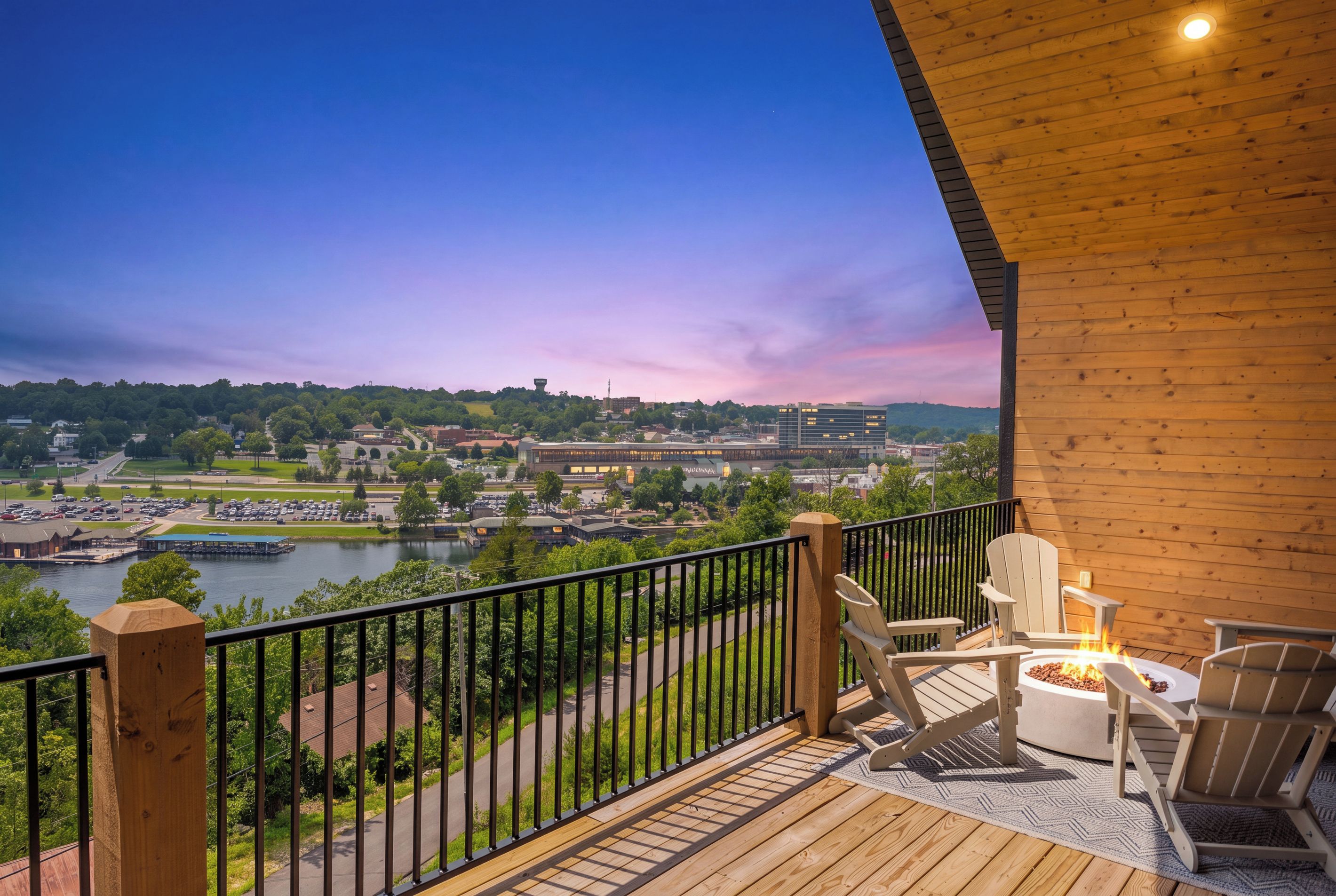 Une terrasse en bois avec des sièges extérieurs et une vue sur une rivière et la ville.