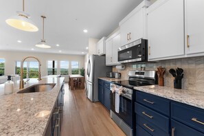 A modern kitchen with stainless steel appliances, a marble countertop, and a view to the outdoors. - Taneycomo Wake & Lake | NEW • Private Pool (Branson)