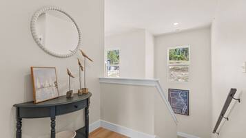 A staircase with a view of the outdoors, a wall-mounted mirror, a console table with a framed picture, and a map.