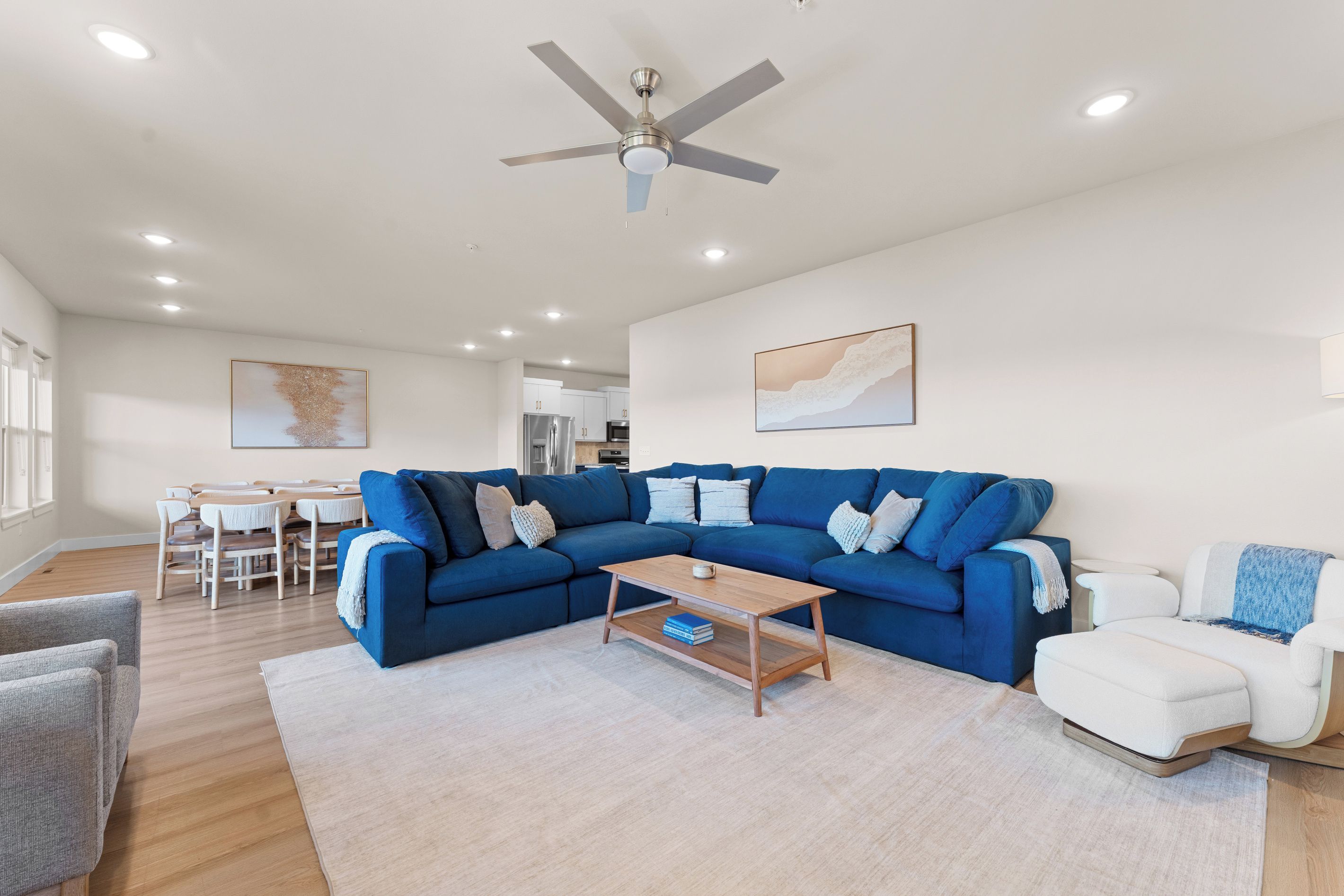 Ein modernes Wohnzimmer mit einem blauen Ecksofa, einem Couchtisch und einem weißen Sessel.