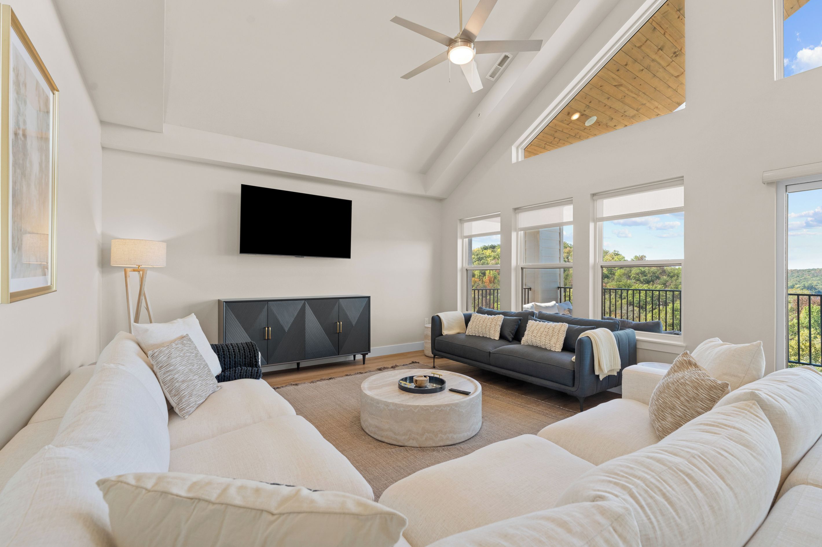 A spacious living room with a large white sofa, a grey sofa, and a black entertainment unit.