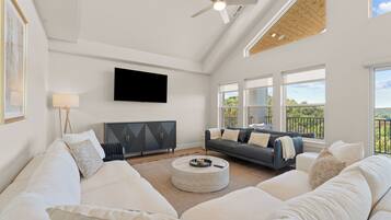 A spacious living room with a large white sofa, a grey sofa, and a black entertainment unit.