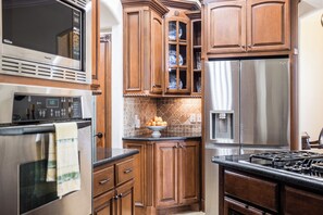 Eine Küche mit Holzausstattung, einem Edelstahlkühlschrank und einer Mikrowelle.
