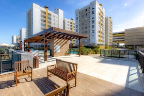 Eine Dachterrasse mit einer hölzernen Pergola, einer Sitzgelegenheit und einem Swimmingpool.