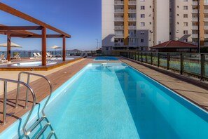 Ein Poolbereich auf dem Dach mit Liegestühlen und einer Holzpergola.