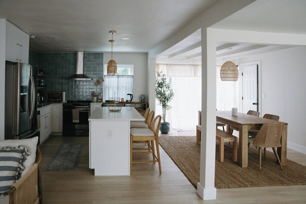 Une cuisine moderne avec un îlot central, une table à manger en bois et des chaises.