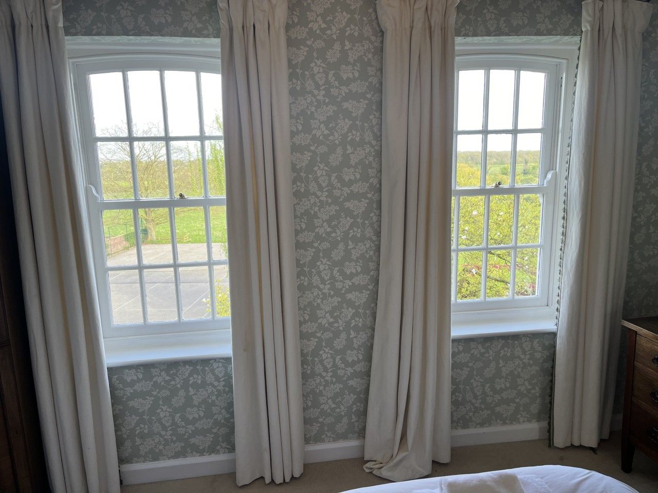 A room with two windows, each with a view of greenery outside.